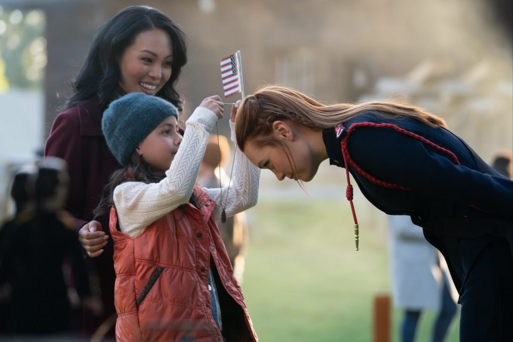Una niña le pone una medalla a una de las protagonistas. Como medalla al honor o tal
